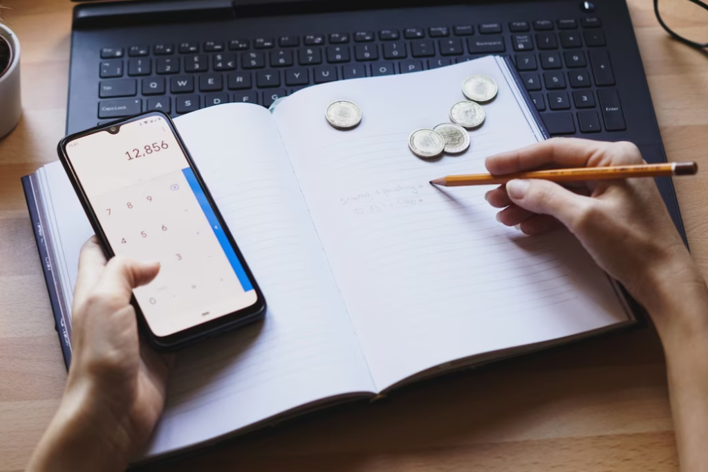 a person is working from home on his personal finances and savings and writes in the notebook