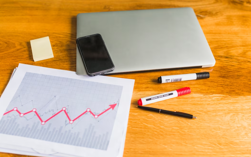 graph with laptop and cellphone over wooden desk