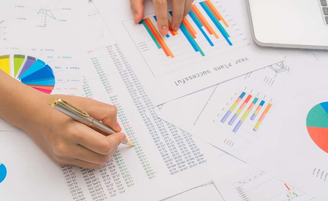 Table of financial documents with a hand pointing at numbers with a pen