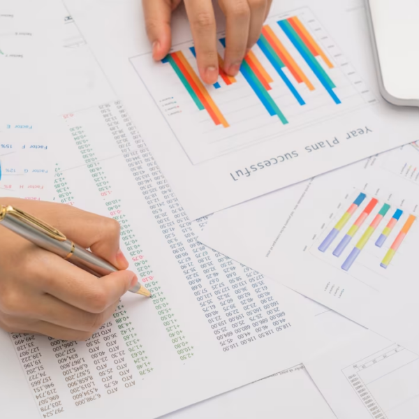 Table of financial documents with a hand pointing at numbers with a pen