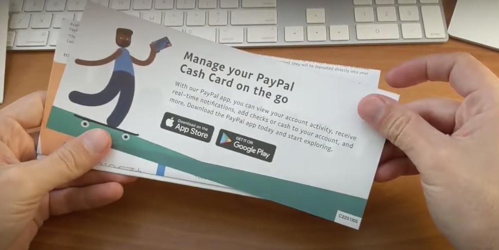 Hand holding a brochure with the text 'Manage your PayPal Cash Card on the go