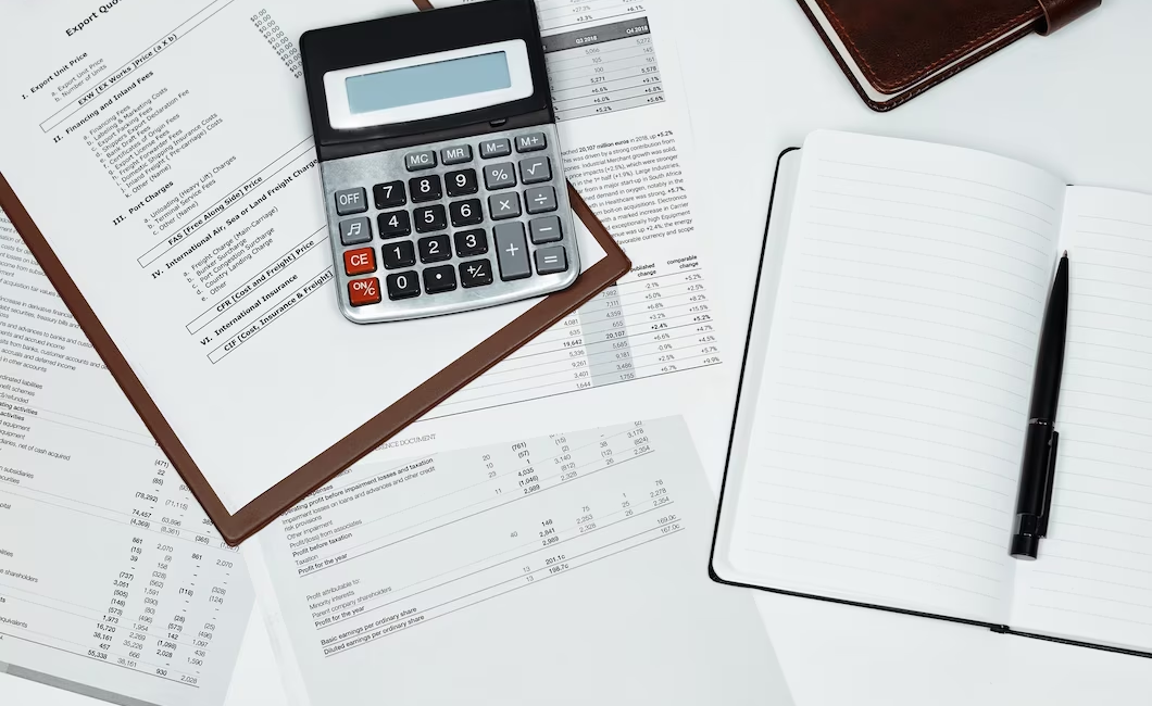 Calculator, notebook, pen, and financial documents scattered on a table