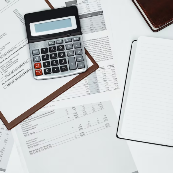 Calculator, notebook, pen, and financial documents scattered on a table