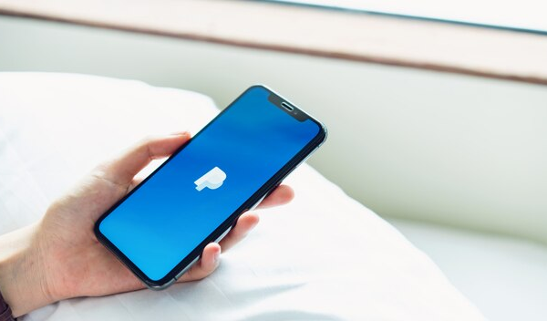 Hand holding a phone with the PayPal logo on the screen