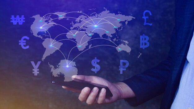 Hand holding a phone with global graphics showing a world map intersected by lines with currency symbols, representing international money transfer