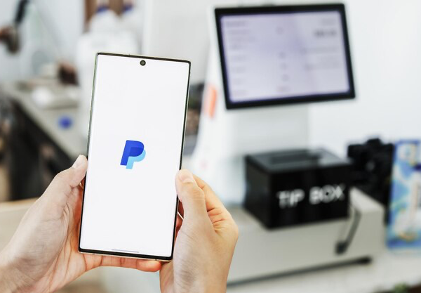 Hands holding smartphone with open PayPal application