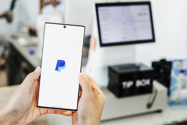 Hands holding smartphone with open PayPal application