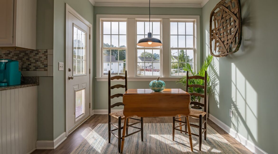 A room with a table, 2 chairs and a wooden picture.